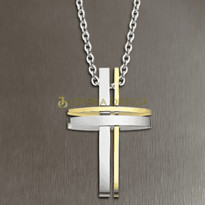 Colgante de cruz oro y plata sobre fondo gris.