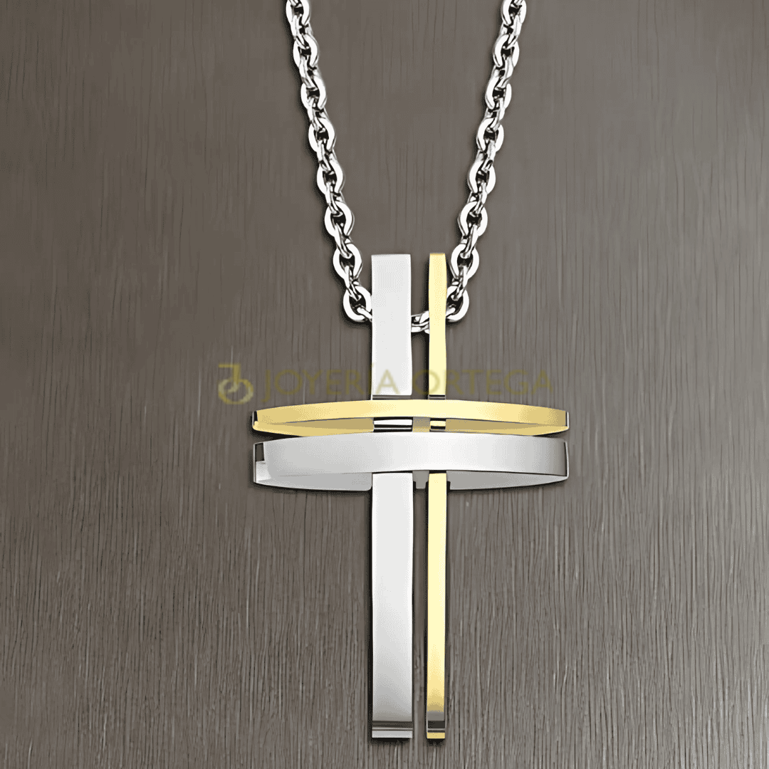 Colgante de cruz oro y plata sobre fondo gris.