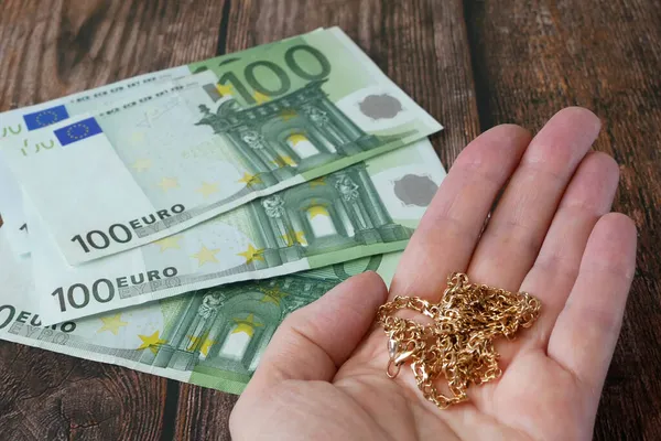 Mano con joyas y billetes de cien euros