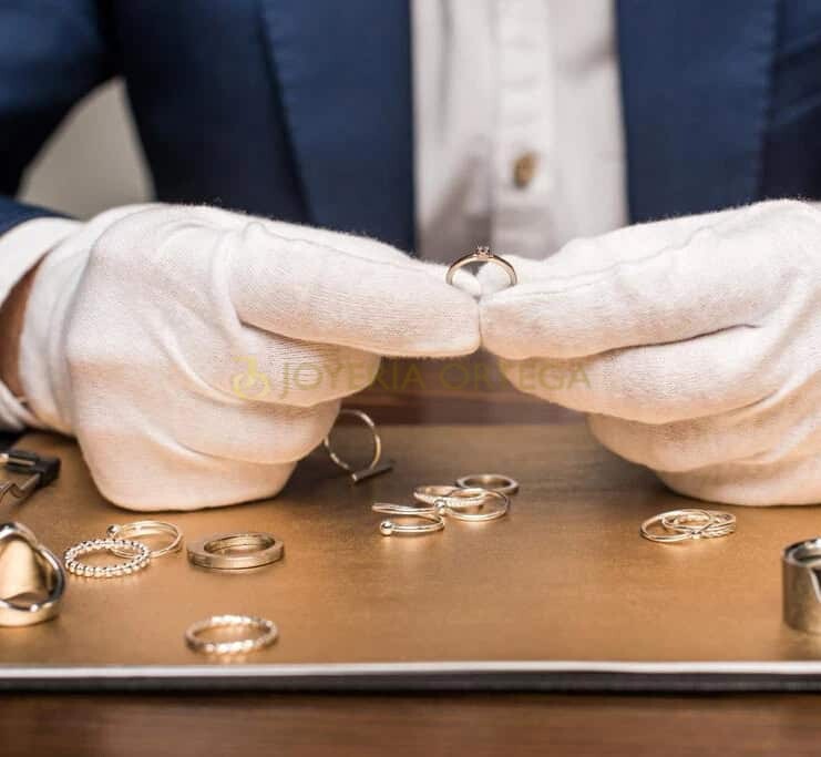 Manos con guantes mostrando anillo de joyería